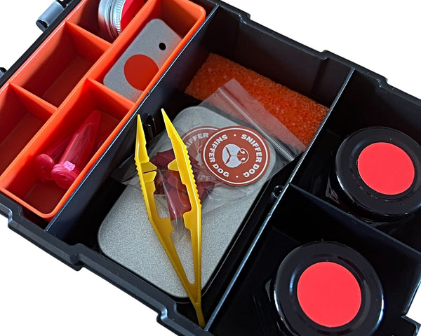 Dog scent training kit containing red-lidded magnetic tins, tweezers, glass vials, KONG chunks, and foam insert in a waterproof organiser.