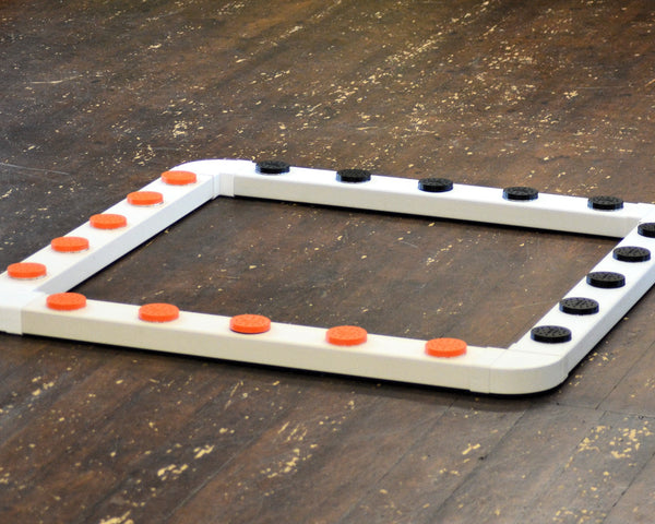 A white sniffer dog system with orange and black vented metal pots and connectors on a wooden floor.