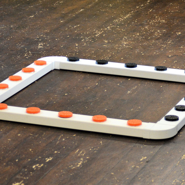 A white sniffer dog system with orange and black vented metal pots and connectors on a wooden floor.